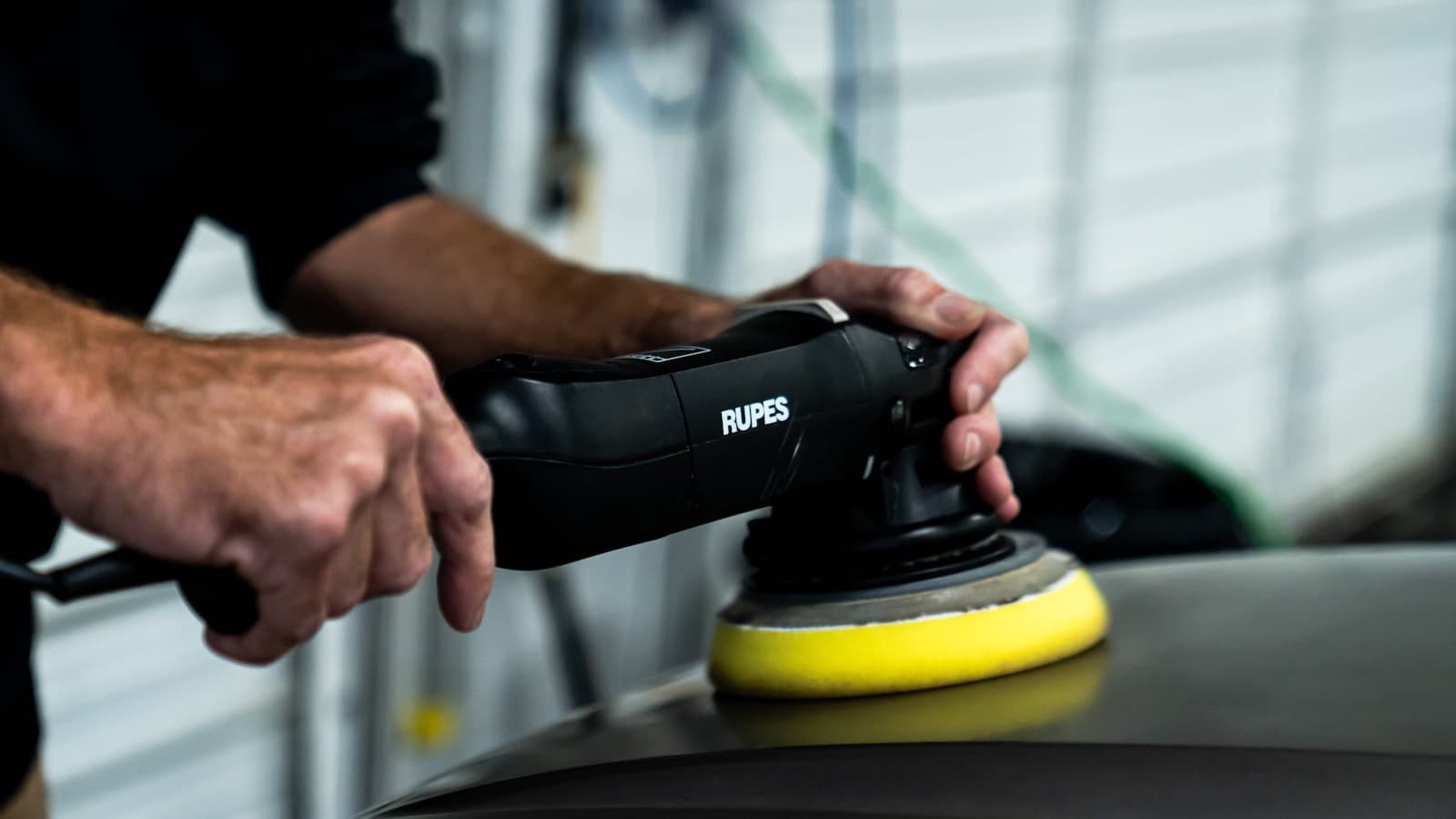 Hantverkare som slipar en bil inför lackering